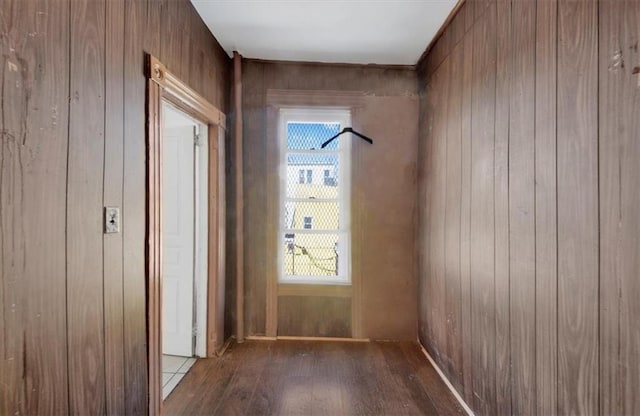hallway featuring wood finished floors, wooden walls, and healthy amount of natural light