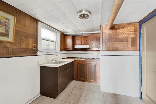kitchen featuring a sink, light tile patterned flooring, and wood walls