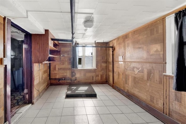 basement with wood walls and light tile patterned floors
