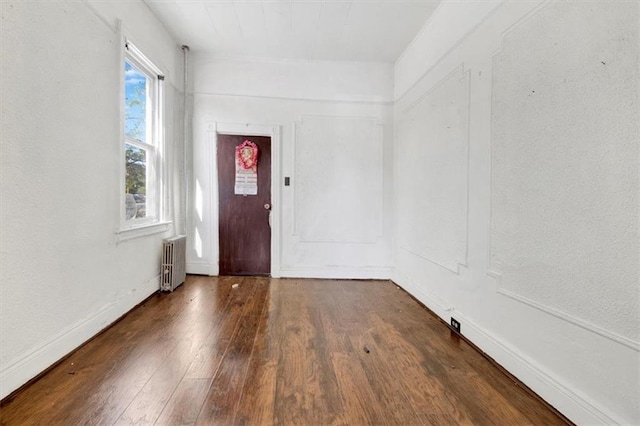 foyer entrance featuring baseboards, hardwood / wood-style floors, and radiator heating unit