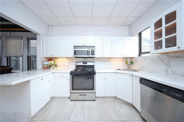 436 76th St, Brooklyn, NY 11209 - kitchen with stainless steel appliances, a sink, a paneled ceiling, a peninsula, and white cabinets