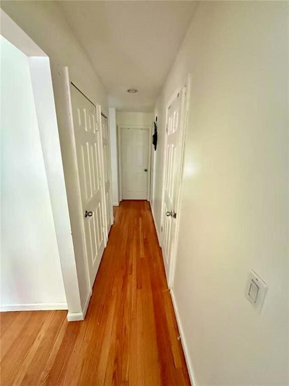 corridor featuring wood finished floors and baseboards