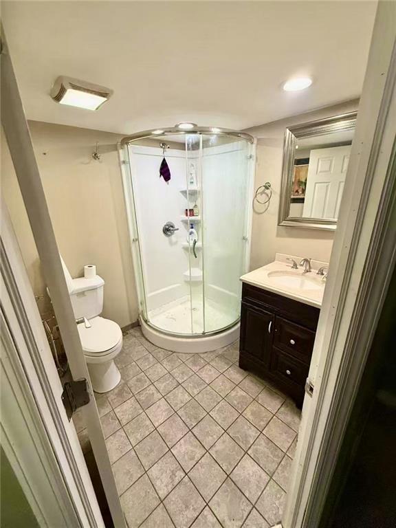 bathroom with tile patterned floors, toilet, vanity, and a stall shower