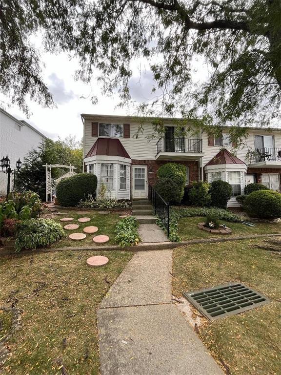 view of front of property featuring a front yard and a balcony