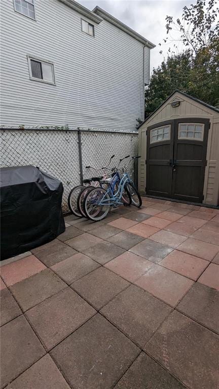 view of patio with a storage shed, an outbuilding, and a grill
