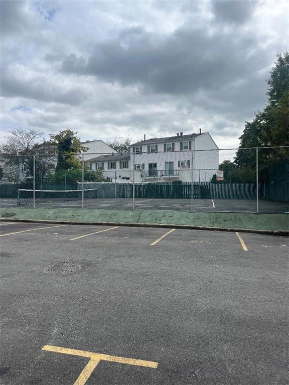 uncovered parking lot featuring fence and a tennis court