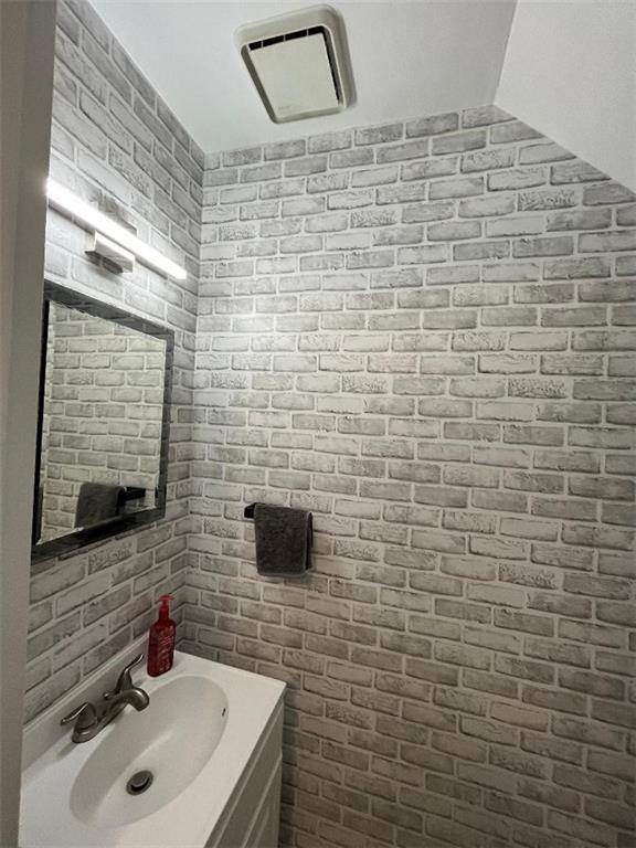 bathroom featuring vanity and brick wall