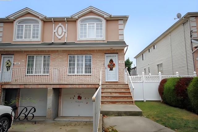 view of property featuring fence, brick siding, concrete driveway, a garage, and stucco siding