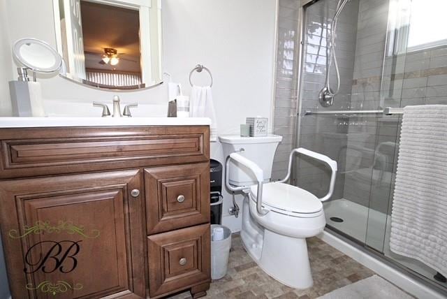 bathroom with a stall shower, vanity, and toilet