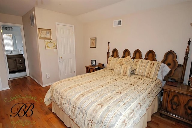 bedroom featuring baseboards, visible vents, a sink, and wood finished floors