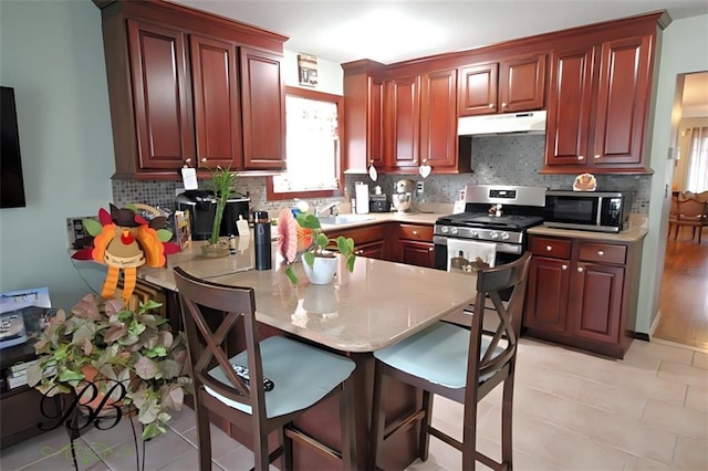 kitchen featuring a wealth of natural light, stainless steel appliances, a peninsula, and under cabinet range hood