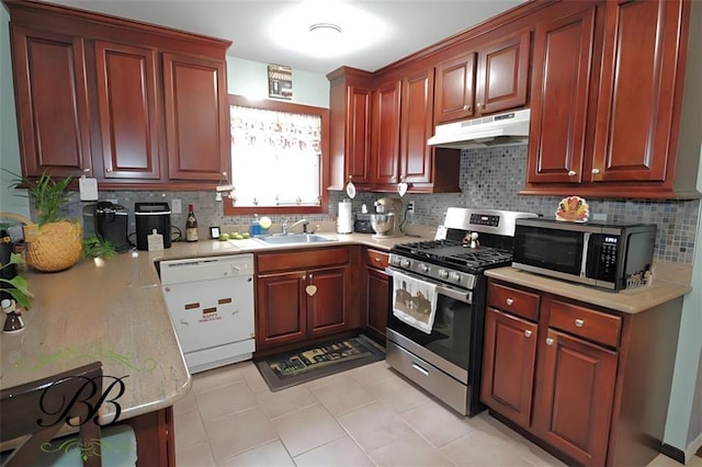 kitchen featuring light countertops, a sink, stainless steel range with gas stovetop, under cabinet range hood, and dishwasher