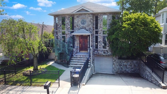 view of front of house with stone siding, fence, concrete driveway, and an attached garage