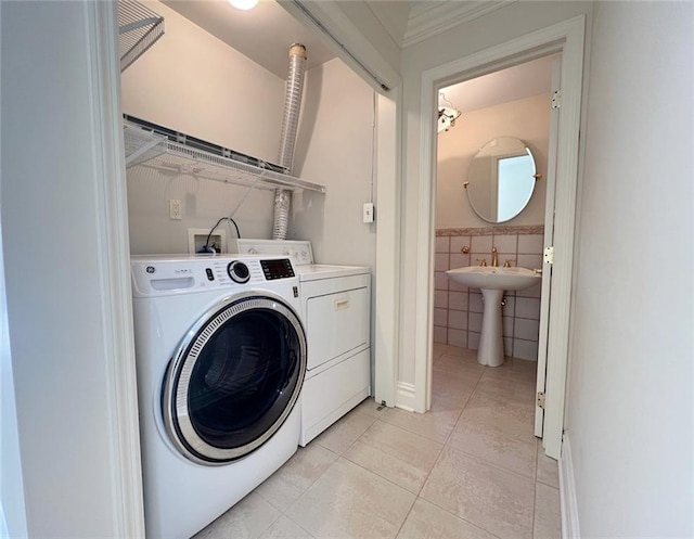 washroom with washing machine and dryer, light tile patterned floors, and tile walls