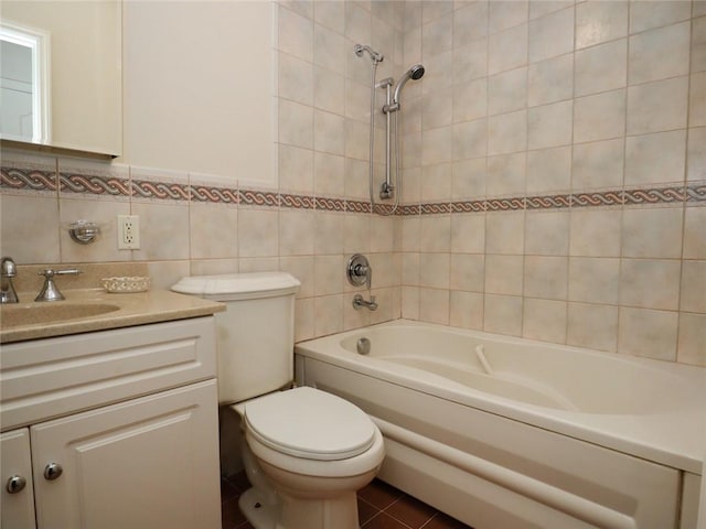 bathroom with tile walls, vanity, toilet, washtub / shower combination, and tile patterned floors