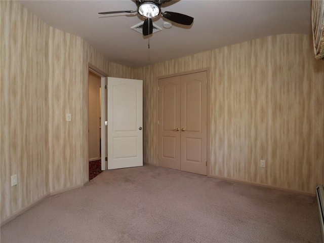 carpeted empty room with a ceiling fan and a baseboard heating unit