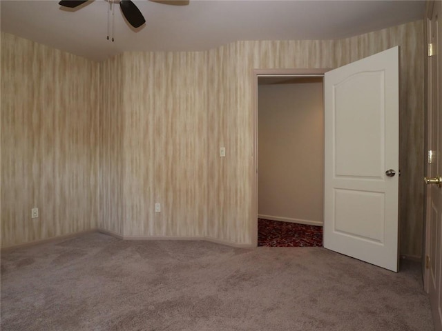 unfurnished room featuring a ceiling fan, carpet floors, wallpapered walls, and baseboards