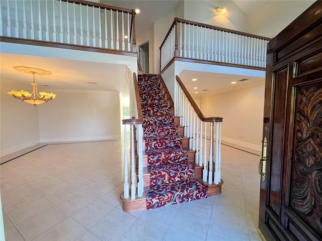 staircase featuring a chandelier, ornamental molding, tile patterned floors, a high ceiling, and baseboards