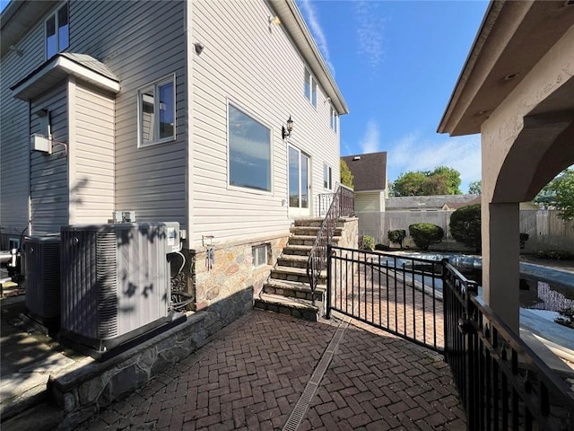 view of property exterior featuring central air condition unit, fence, and a patio