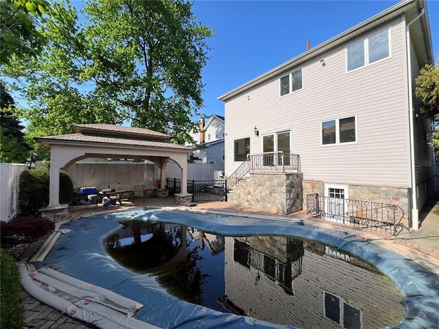 rear view of property with a gazebo, a fenced backyard, a patio area, and stairs