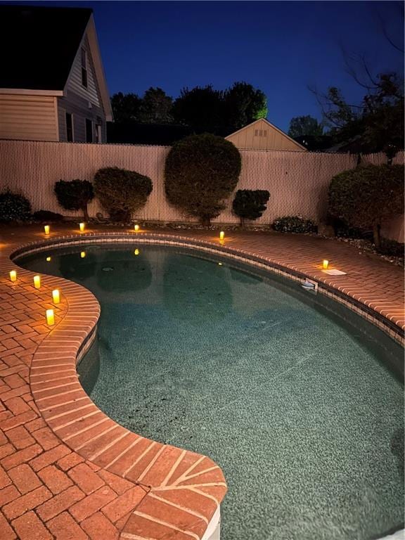 pool at twilight featuring a fenced backyard