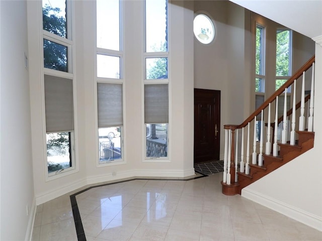 entrance foyer with baseboards, a high ceiling, stairs, and inlaid floor details