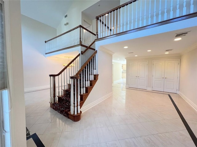 stairs featuring baseboards, tile patterned flooring, a towering ceiling, recessed lighting, and crown molding