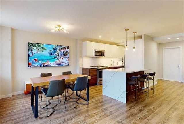 dining space featuring light wood-style flooring, baseboards, and recessed lighting