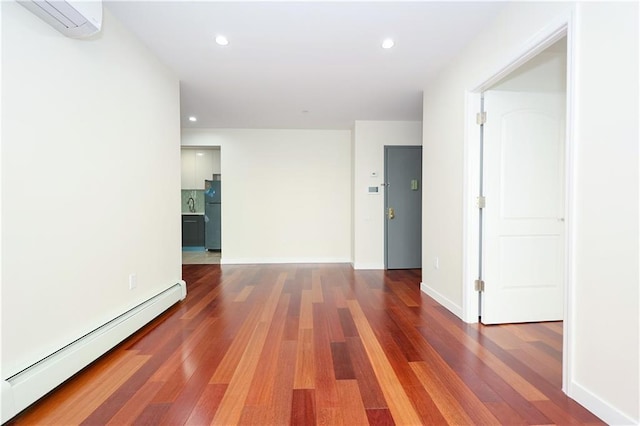 empty room with a baseboard radiator, recessed lighting, and wood finished floors
