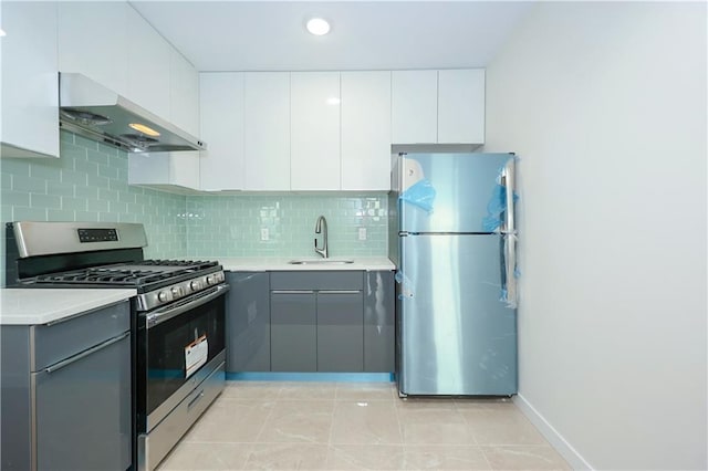 kitchen with a sink, stainless steel appliances, gray cabinets, exhaust hood, and backsplash