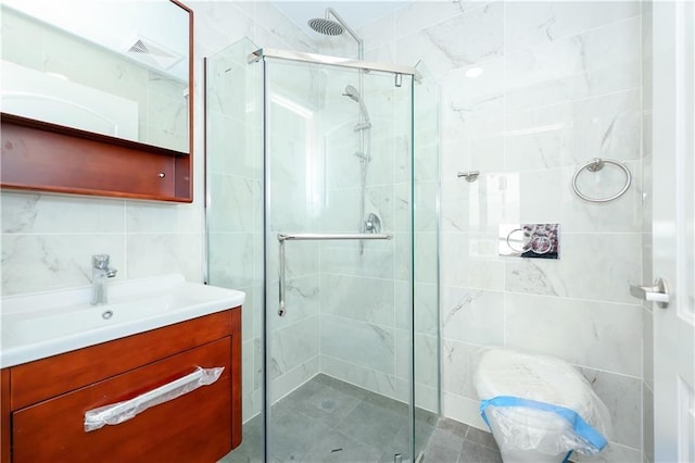 full bath featuring tile walls, vanity, and a stall shower