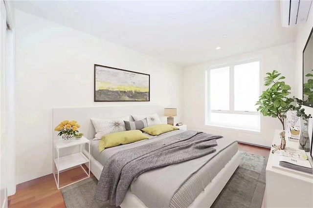 bedroom featuring light wood-type flooring, a wall unit AC, and recessed lighting