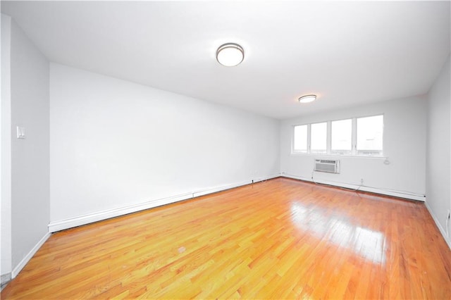 345 92nd St Unit 3B, Brooklyn, NY 11209 - spare room featuring wood finished floors, a wall mounted air conditioner, a baseboard radiator, and baseboards
