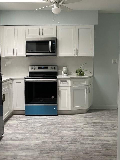 1669 Holly St, Baldwin, NY 11510 - kitchen featuring stainless steel appliances, a ceiling fan, light countertops, and white cabinetry