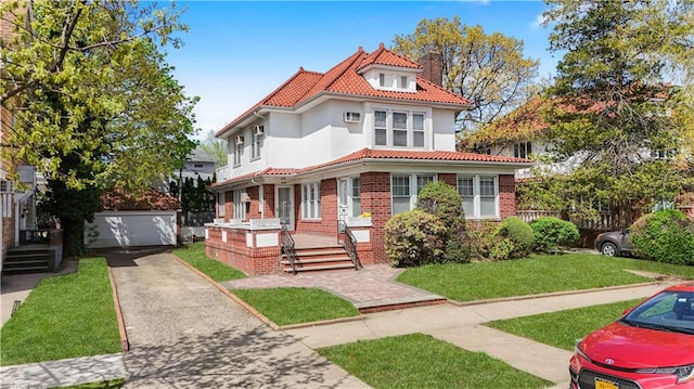 3098 Bedford Ave, Brooklyn, NY 11210 - mediterranean / spanish-style house with a tiled roof, stucco siding, a detached garage, brick siding, and an outdoor structure