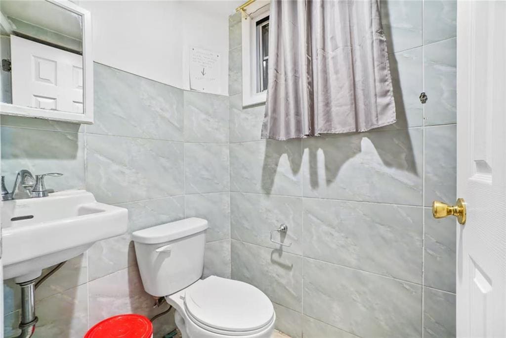 half bath with tile walls and toilet