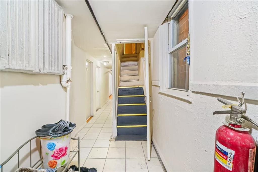 hall featuring light tile patterned flooring and stairs