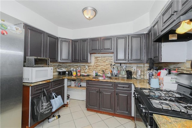 kitchen with black range with gas cooktop, white microwave, decorative backsplash, a sink, and under cabinet range hood