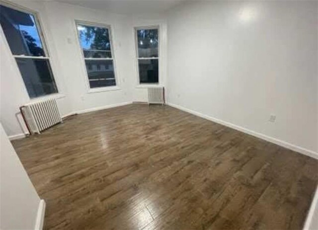 spare room featuring dark wood-type flooring and baseboards