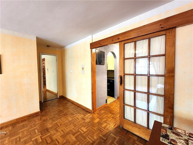 spare room featuring arched walkways and baseboards