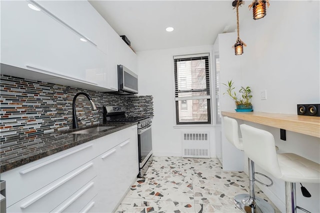 2546 E 13th St Unit A11, Brooklyn, NY 11235 - kitchen featuring stainless steel appliances, tasteful backsplash, white cabinetry, dark stone countertops, and recessed lighting