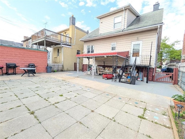 back of property featuring fence, a patio area, a gate, and a chimney