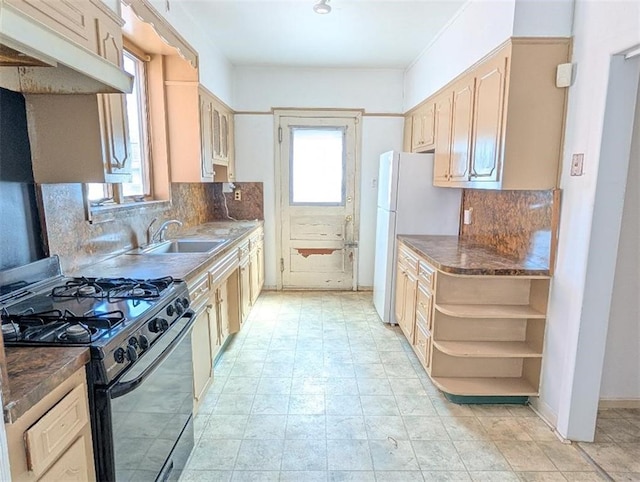 kitchen featuring black range with gas stovetop, a sink, freestanding refrigerator, open shelves, and backsplash