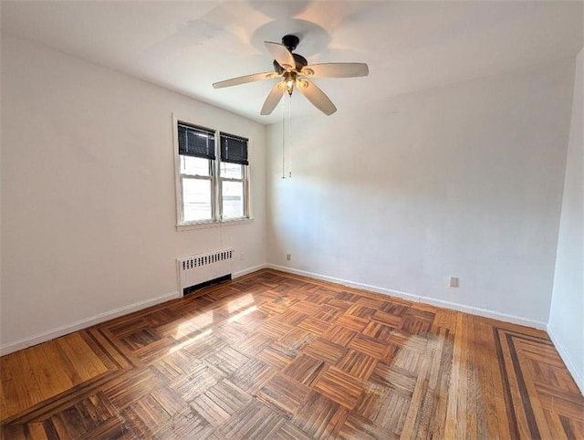 empty room featuring radiator heating unit, baseboards, and ceiling fan