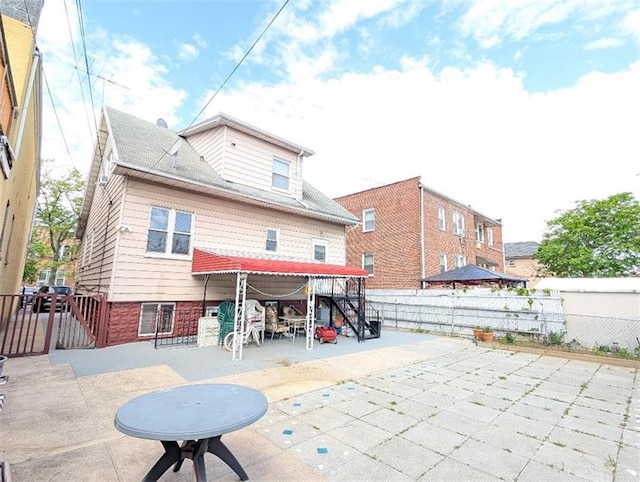 rear view of house featuring a patio area, a fenced backyard, and a gate
