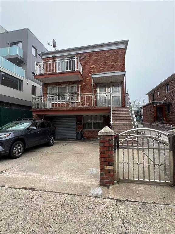view of property with brick siding, driveway, stairs, a gate, and a fenced front yard