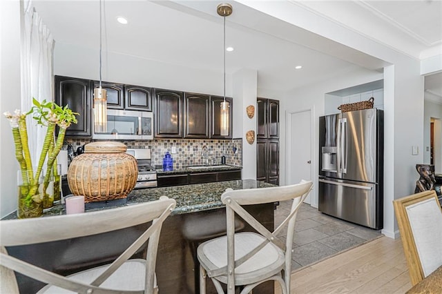 138 Wakeman Pl, Brooklyn, NY 11220 - kitchen featuring appliances with stainless steel finishes, dark stone counters, backsplash, light wood finished floors, and recessed lighting