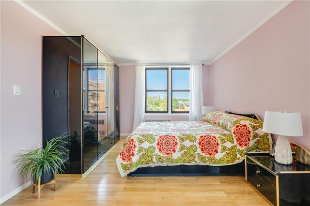 bedroom with wood finished floors, crown molding, and baseboards