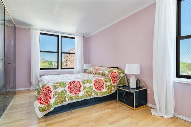 bedroom featuring crown molding, wood finished floors, and baseboards