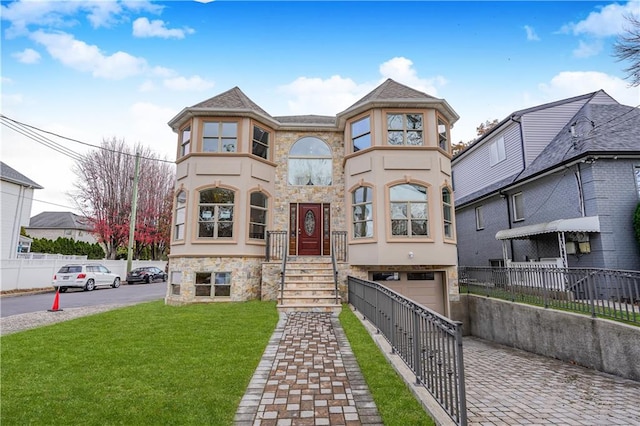 view of front of house featuring an attached garage, stucco siding, stone siding, and driveway